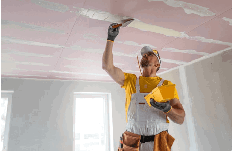 Drywall contractor applying a smooth finish to a ceiling surface.